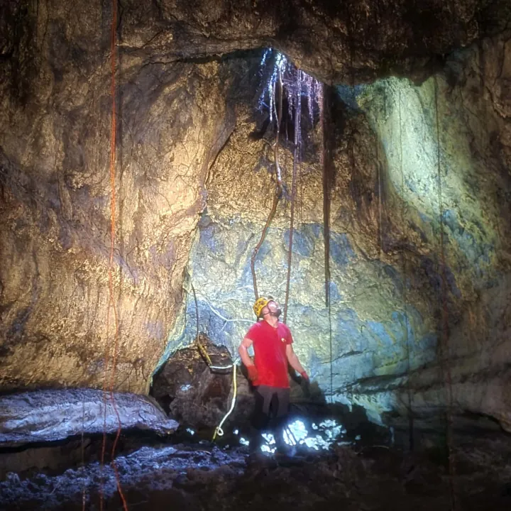 Spéléologue explorant une salle du tunnel de lave de Citron Galet à La Réunion avec puits de lumière